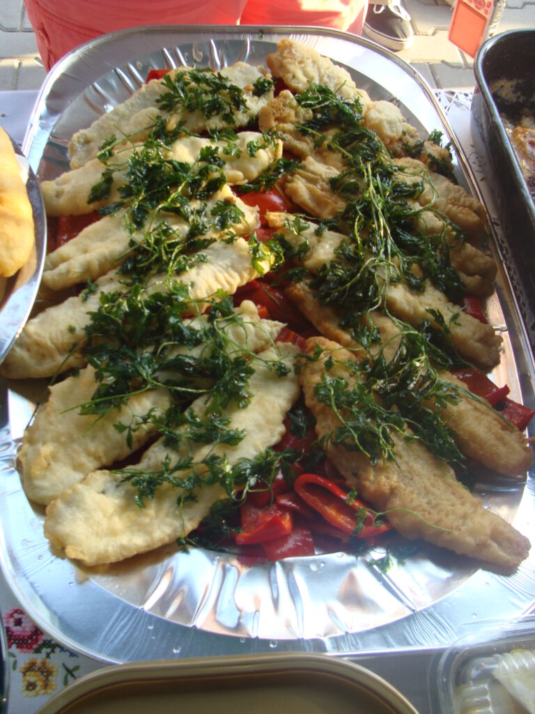 Grilled fish with greens on a metal platter.