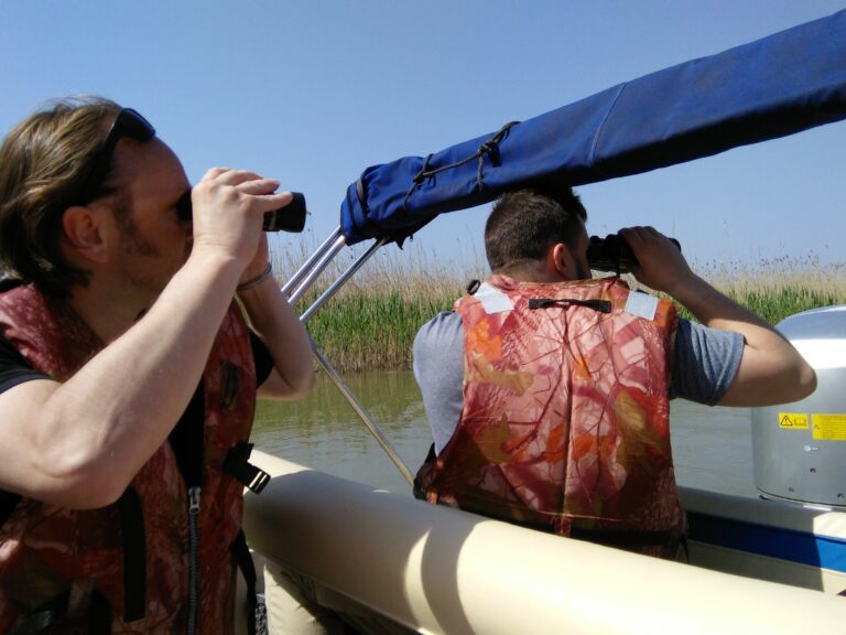 People observing nature with binoculars from a boat.